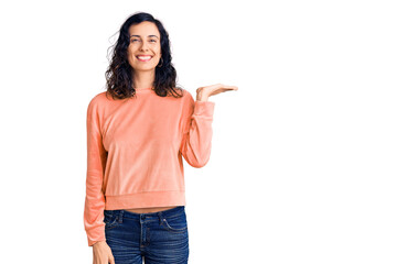 Young beautiful hispanic woman wearing casual clothes smiling cheerful presenting and pointing with palm of hand looking at the camera.