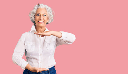 Senior grey-haired woman wearing casual clothes gesturing with hands showing big and large size sign, measure symbol. smiling looking at the camera. measuring concept.