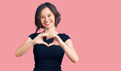 Young beautiful girl wearing casual clothes smiling in love showing heart symbol and shape with...