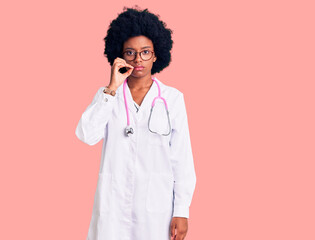 Young african american woman wearing doctor coat and stethoscope mouth and lips shut as zip with...