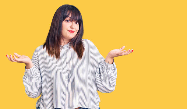 Young plus size woman wearing casual clothes clueless and confused expression with arms and hands raised. doubt concept.