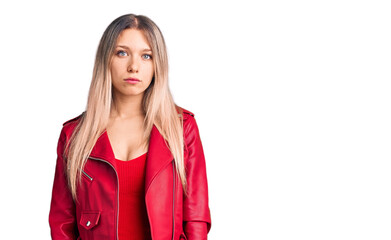 Young beautiful blonde woman wearing red leather jacket with serious expression on face. simple and natural looking at the camera.