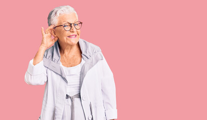 Senior beautiful woman with blue eyes and grey hair wearing casual clothes and glasses smiling with hand over ear listening an hearing to rumor or gossip. deafness concept.