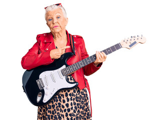 Senior beautiful woman with blue eyes and grey hair wearing a modern look playing electric guitar pointing with hand finger to the side showing advertisement, serious and calm face