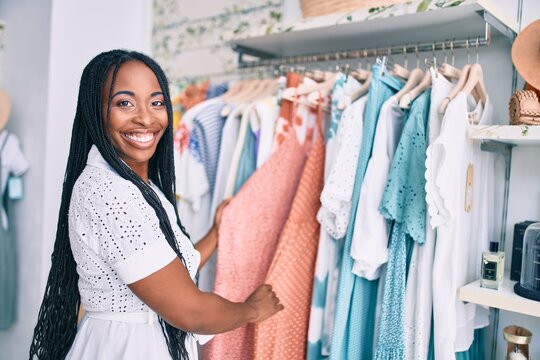 Young african american woman smiling happy holding clothes at clothing store