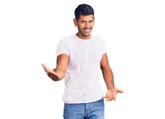 Young latin man wearing casual clothes smiling cheerful with open arms as friendly welcome, positive and confident greetings