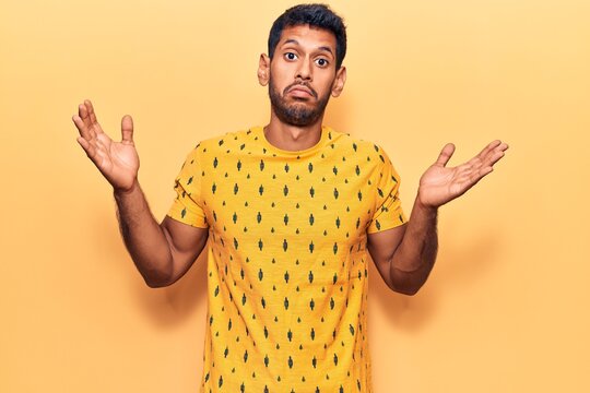 Young latin man wearing casual clothes clueless and confused with open arms, no idea and doubtful face.