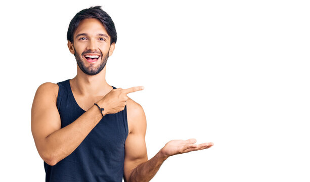 Handsome hispanic man wearing casual clothes amazed and smiling to the camera while presenting with hand and pointing with finger.