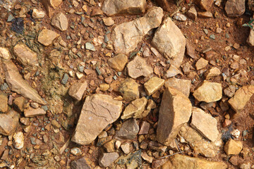 Wet ground, yellow soil, there are many small stones, details of the texture
