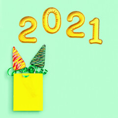 Color candy creative for New Year or Christmas. Lollipops shaped like Christmas tree and metallic golden inflatable figure 2021 on neo mint colored paper background. Top view.