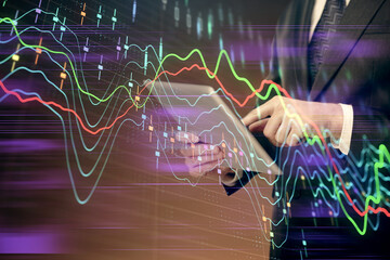 Double exposure of man's hands holding and using a digital device and forex graph drawing. Financial market concept.