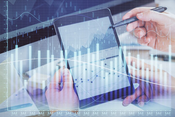 Double exposure of man's hands holding and using a phone and financial chart drawing. Market analysis concept.