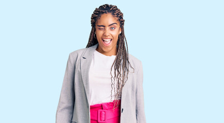 Young african american woman with braids wearing business clothes winking looking at the camera...