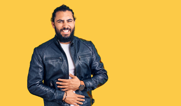Young arab man wearing casual leather jacket smiling and laughing hard out loud because funny crazy joke with hands on body.