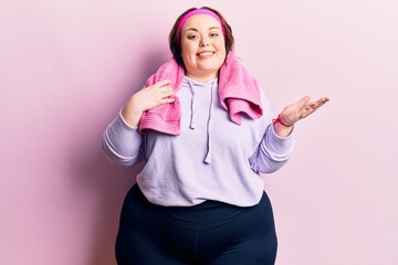 Young plus size woman wearing sportswear and towel celebrating achievement with happy smile and...