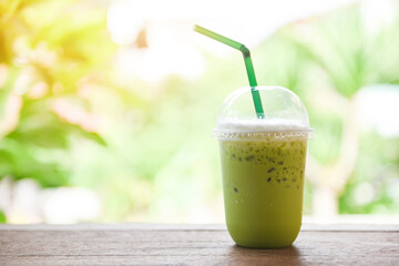 Green tea smoothie - Matcha green tea with milk on plastic glass on the wooden table and nature...