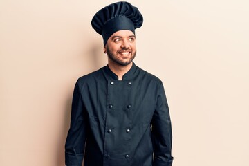 Young hispanic man wearing cooker uniform looking to side, relax profile pose with natural face and confident smile.