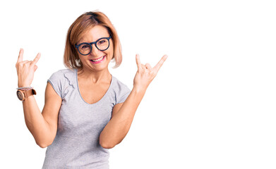 Young blonde woman wearing casual clothes shouting with crazy expression doing rock symbol with hands up. music star. heavy concept.