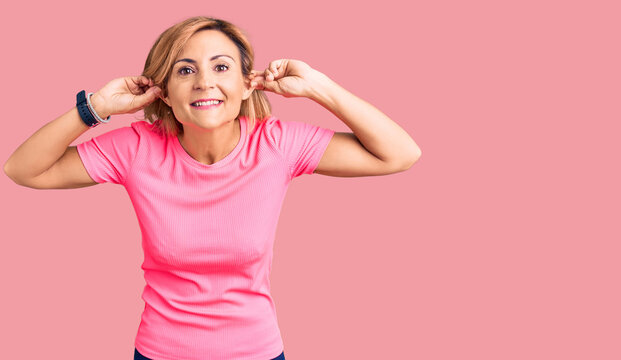 Young blonde woman wearing sportswear smiling pulling ears with fingers, funny gesture. audition problem