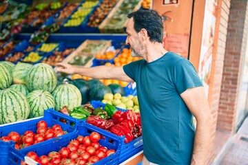 Middle age man with beard smiling happy shopping vegetables at the grocery supermarket