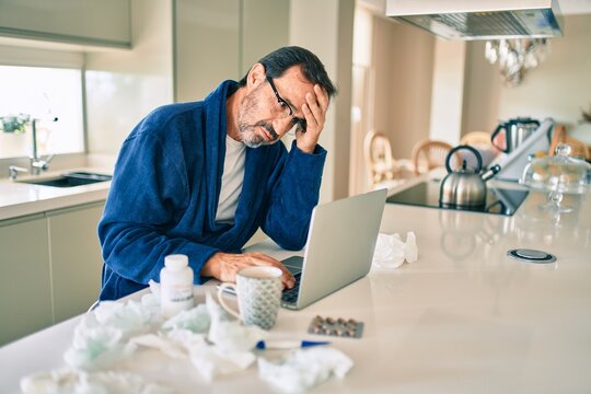 Middle age man feeling sick with cold and fever at home, ill with flu disease working from home