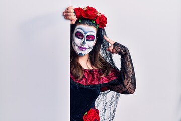 Young woman wearing day of the dead custome holding blank empty banner smiling pointing to head with one finger, great idea or thought, good memory