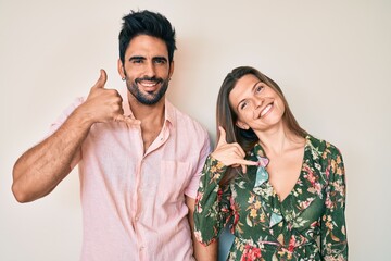 Beautiful young couple of boyfriend and girlfriend together smiling doing phone gesture with hand and fingers like talking on the telephone. communicating concepts.