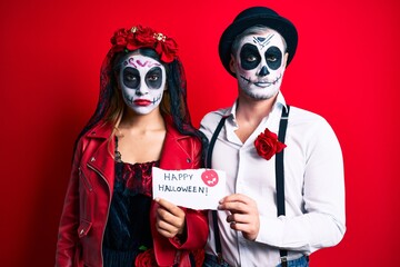 Couple wearing day of the dead costume holding happy halloween paper skeptic and nervous, frowning upset because of problem. negative person.