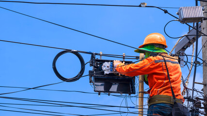 Rear view of technician on wooden ladder is working to install fiber optic and splitter box on...