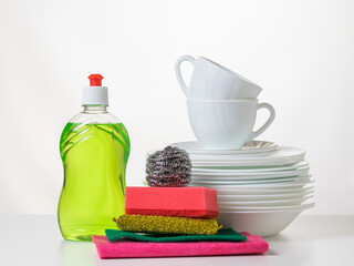 Obraz na płótnie Canvas Green dishwashing gel, rags and a set of plates on a light background.