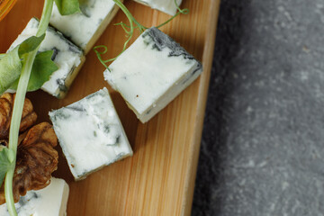 Close-up of a cheese plate. 4 types of cheese, soft white brie cheese, camembert, semi-soft briques, blue, roquefort, hard cheese