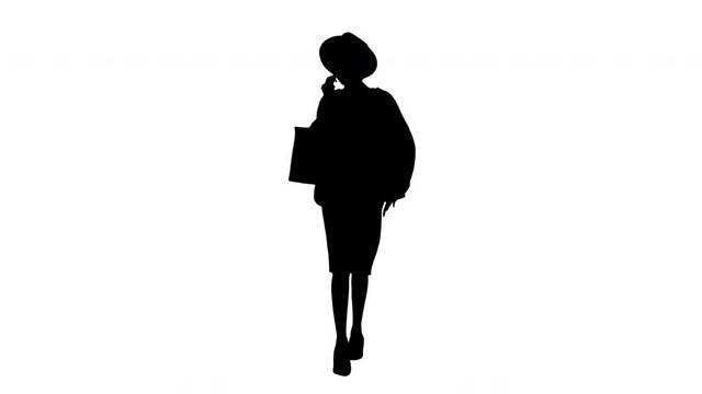 African american girl in oversized knitwear and hat talking on her phone while walking with shopping bags, Alpha Channel