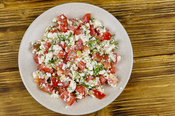 Tasty salad of tomato, cottage cheese, dill and olive oil on wooden table. Top view