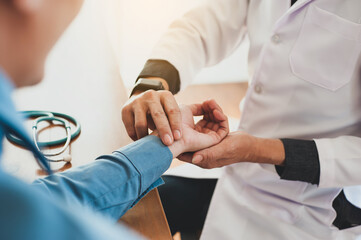 The doctor measures the pulse on the patient's wrist.