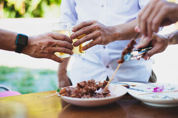 Young man holding a beer glass and drinking with his friends at an outdoor party at home.