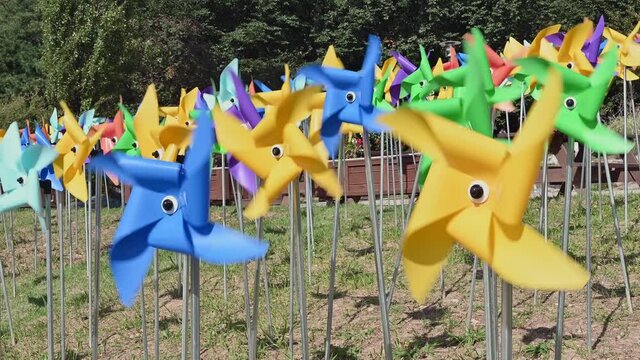 Multicolored pinwheels spinning in the wind on the lawn.