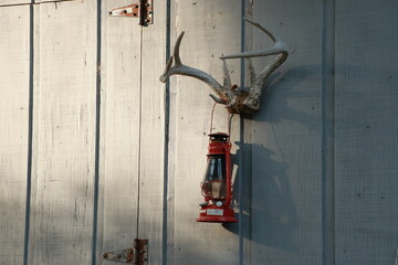 Old red lantern hanging on deer antlers on an old midwestern shed