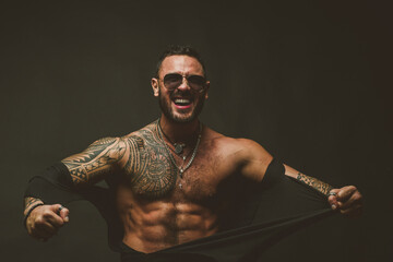 Furious man isolated on black. Muscular guy with sexy torso ripped shirt.