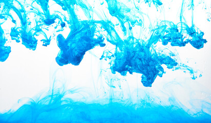 Closeup of a blue ink in water in motion isolated on white. Ink swirling underwater. Colored abstract smoke explosion effect. Abstract background with copy space..