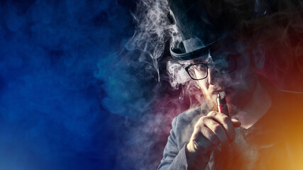 A man in a top hat smokes an electronic cigarette and looks at the camera. VAPE shop. Vaper on a dark background. Place for the text. A serious man with an e-cigarette.