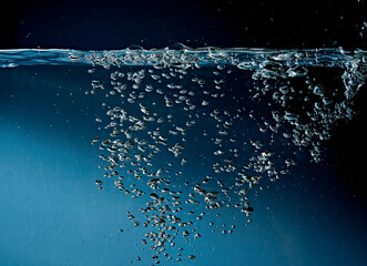Close up of clean blue water and splash with bubbles of air isolated on white background. Diet, health and nature concept. Copy space..