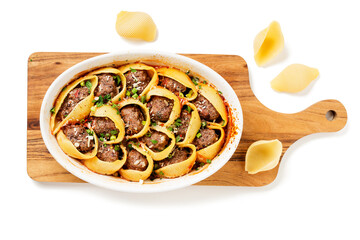Pasta shells stuffed with minced meat . White baking dish on cutting board. isolated on white background