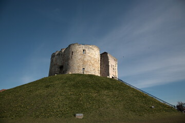 Fototapeta na wymiar View of York Clifford's Tower with green grass and wild flowers on the hill during early Spring in York, Yorkshire, England, UK