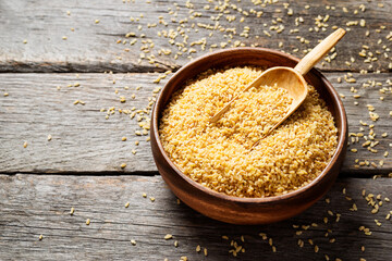 Raw bulgur in wooden bowl. Healthy gluten free product. Concept of healthy eating. Organic wheat grains product.