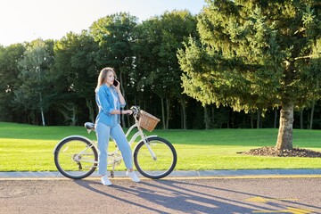 Young serious woman on the road with bike talking on phone