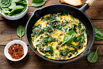 Omelette with baby spinach in cast iron pan, healthy breakfast . 