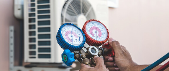 Air repair mechanic using measuring pressure gauge equipment for filling home air conditioner after...