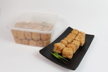 tahu pong is a type of hollow tahu goreng (fried tofu) cut into small pieces. On black plate. Indonesian street food.