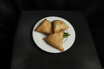 Curry Puff. South east Asia origin food concept homemade chicken Curry puffs on white plate and black background 