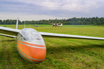 a glider is landed on a green grass of  an airdrome field in russian countryside